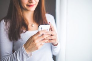 close up portrait of a young woman typing a text message on mobile phone